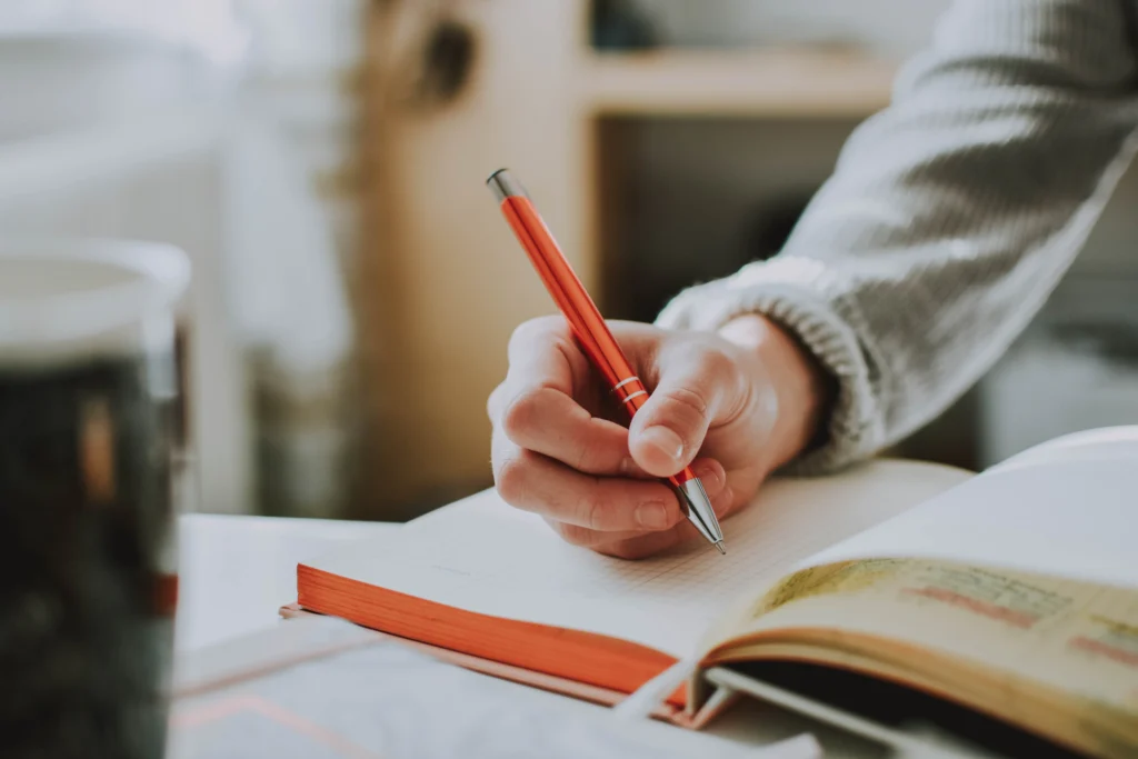 Mão com caneta escrevendo em caderno