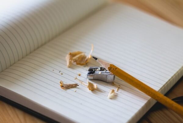 caderno na mesa e lápis apontado em cima