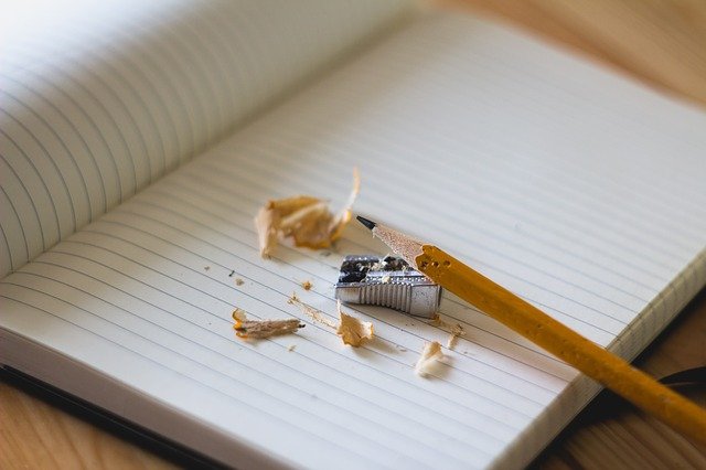 caderno na mesa e lápis apontado em cima