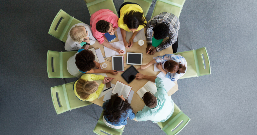Vista de cima de estudantes em roda estudando com livros e tablets