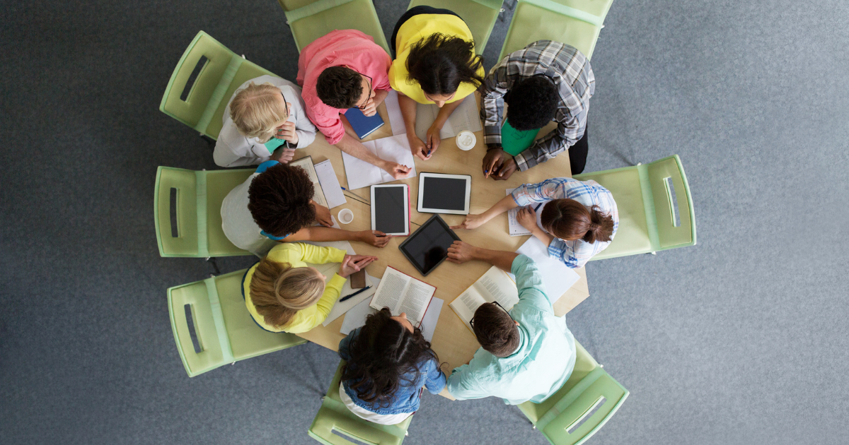 Vista de cima de estudantes em roda estudando com livros e tablets